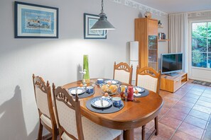 A dining area with a wooden table, chairs, and a television in the corner.