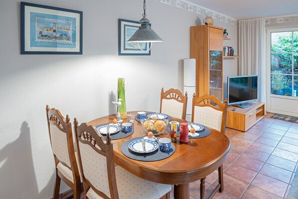 Un coin repas avec une table en bois, des chaises et un téléviseur dans un coin.