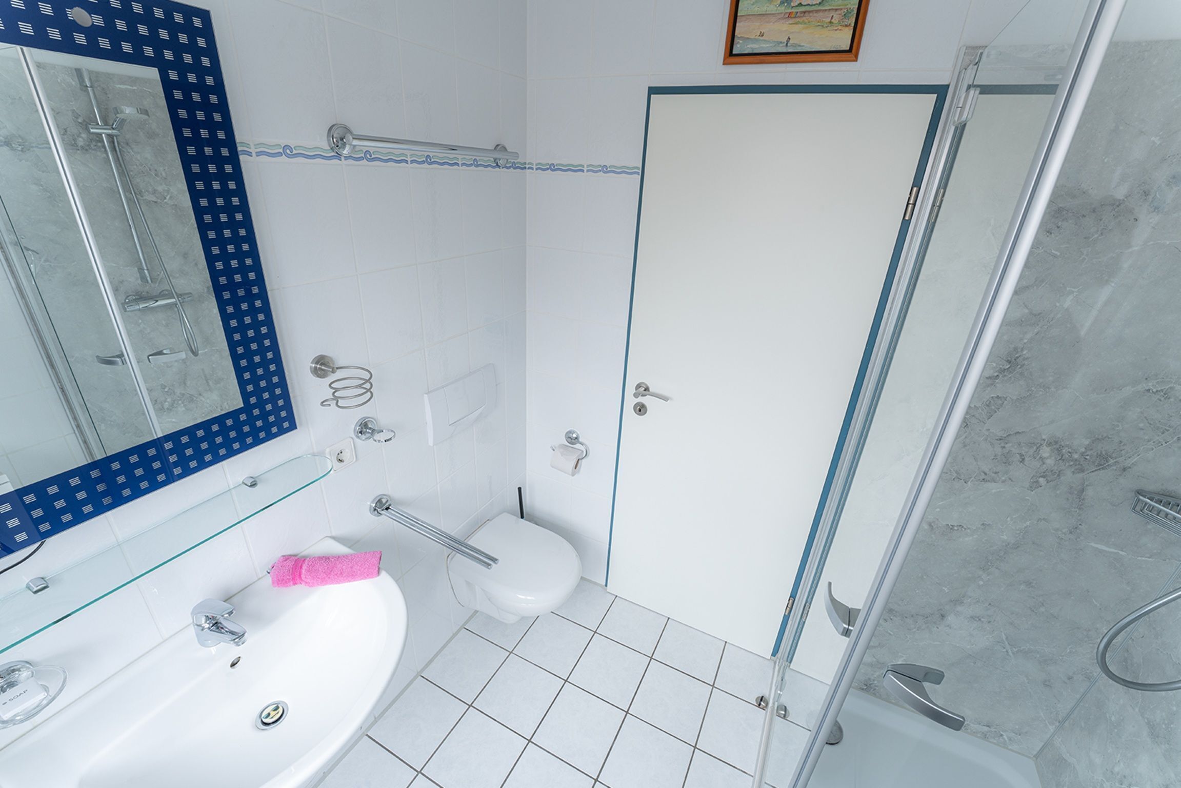 A modern bathroom with a glass shower enclosure, a white sink, and a toilet.