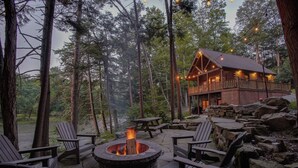 Un chalet doté d’un foyer extérieur, de sièges pour profiter de l’extérieur et d’un mur en pierre.