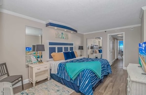 A bedroom with a large bed, bedside tables, a nightstand, a chair, a rug, and a television.