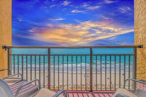 A balcony with a view of the ocean and a sunset sky.