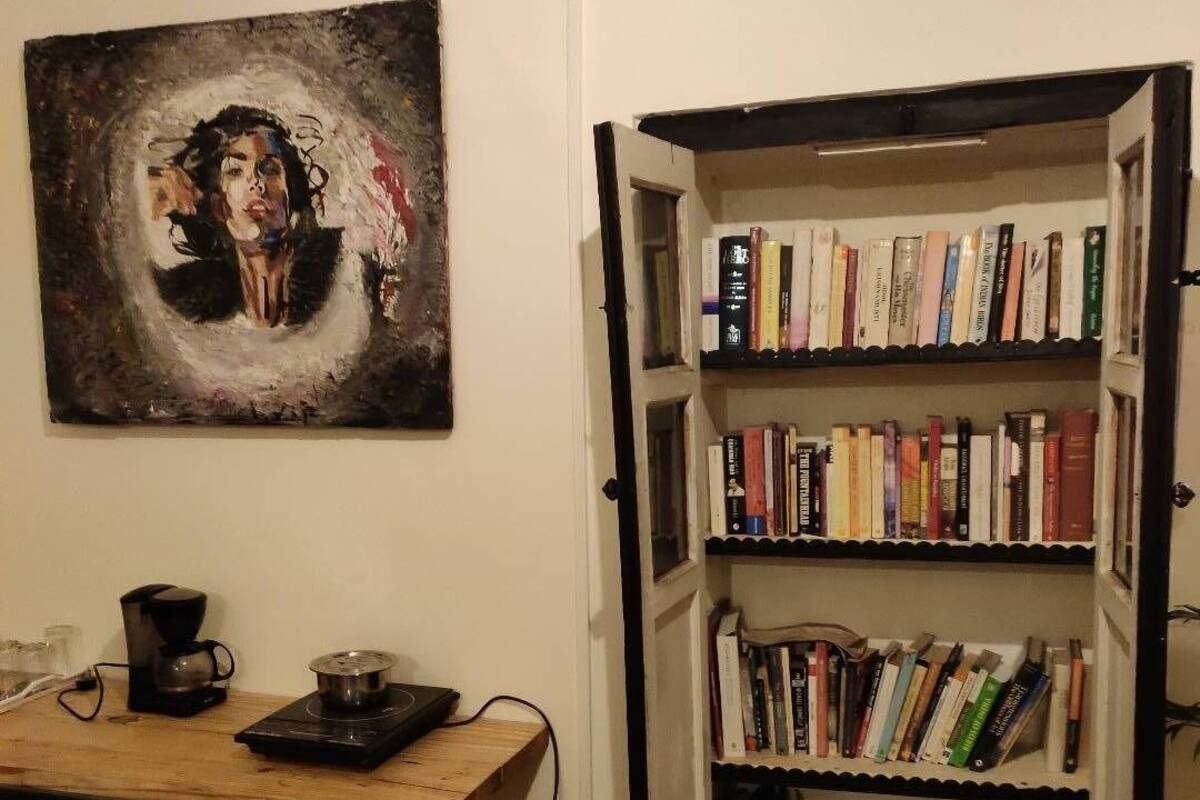 Une pièce avec une bibliothèque remplie de livres, une machine à café et un tableau accroché au mur.