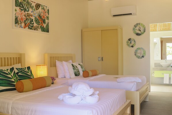 Habitación de hotel con dos camas, un cuadro grande, un armario y un baño visible a través de una puerta abierta.