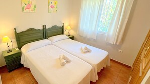 A double room with two beds, a nightstand with a lamp, and a window with curtains. - 0676 Villa Molins Tauro (Denia)
