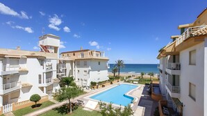 A resort with a swimming pool, multiple balconies, and a view of the sea.