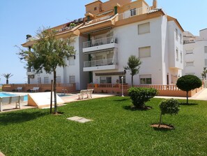 A multi-story building with a swimming pool, outdoor seating, and well-maintained landscaping. - 0770 ap. Talima 1 bedroom (Denia)