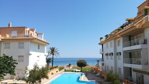 A swimming pool with a view of the sea, surrounded by buildings with balconies and a clear sky. - 0770 ap. Talima 1 bedroom (Denia)