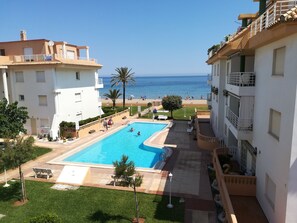 A swimming pool with a view of the sea, surrounded by buildings with balconies. - 0770 ap. Talima 1 bedroom (Denia)