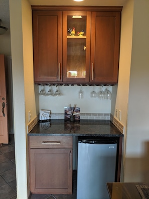 Kitchen area with a central shelf, stainless steel dishwasher, and wine glasses on the countertop.