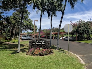 Enter a tranquil oasis with a welcoming entrance, lush tropical plants, and a spacious parking area.