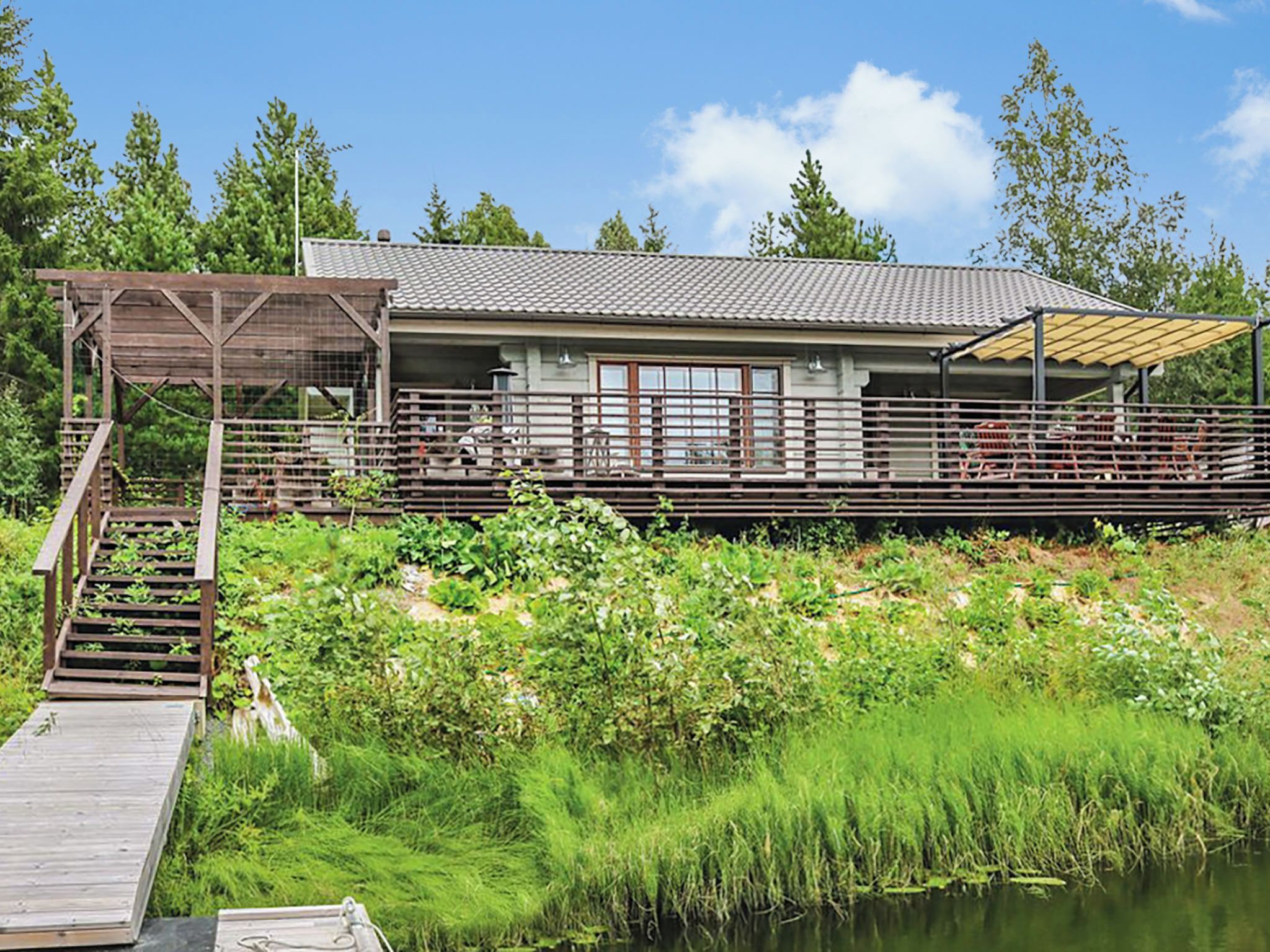 Een gebouw met een overdekt terras en een houten trap naar een steiger.