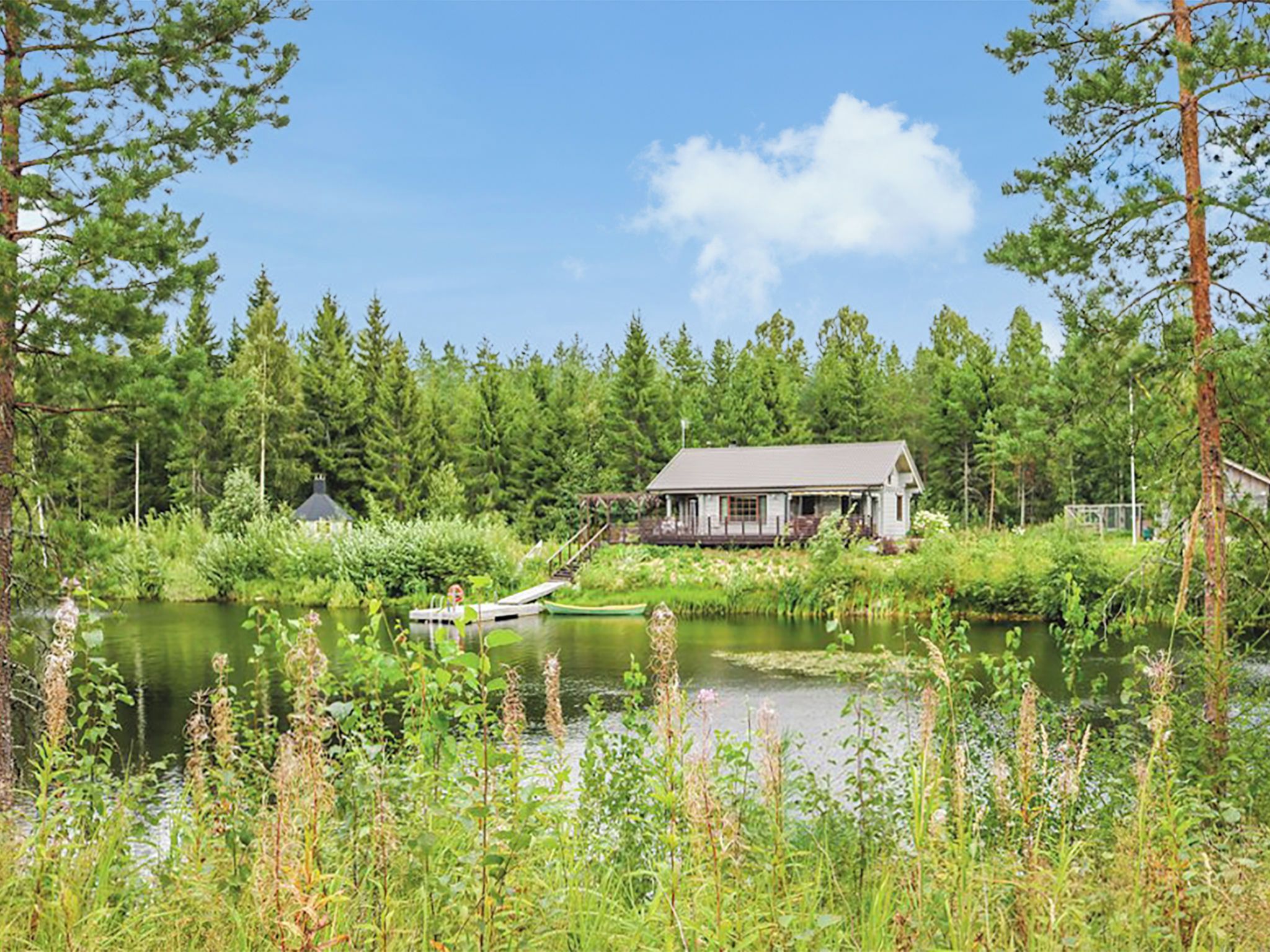 Ein Haus am See mit einem Steg und einem kleinen Boot.