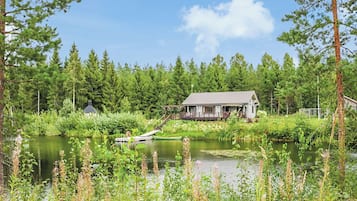 Ein Haus am See mit einem Steg und einem kleinen Boot.