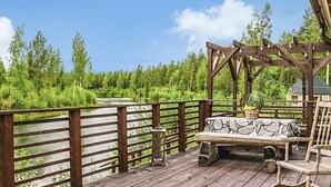 A wooden deck with a bench and a rocking chair, overlooking a river and surrounded by greenery. - Ruuhikari by Interhome (Ulvila)
