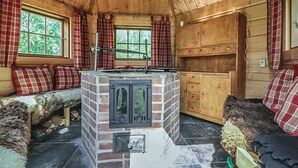A cozy cabin interior with a brick fireplace, wooden furniture, and plaid curtains. - Ruuhikari by Interhome (Ulvila)