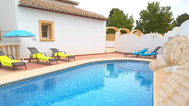 Una piscina con sillas de descanso, techo de baldosas y una escultura de piedra.