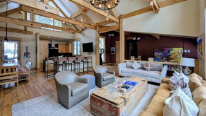 A spacious living area with high ceilings, wooden beams, a chandelier, and a cozy seating arrangement. - Custom Keystone Retreat – Summer Events/Hot Tub (Keystone)