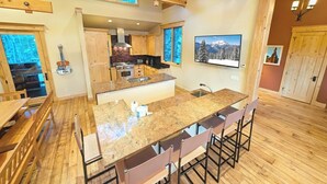 A spacious kitchen with a large island, wooden flooring, and a high ceiling with exposed beams. - Custom Keystone Retreat – Summer Events/Hot Tub (Keystone)