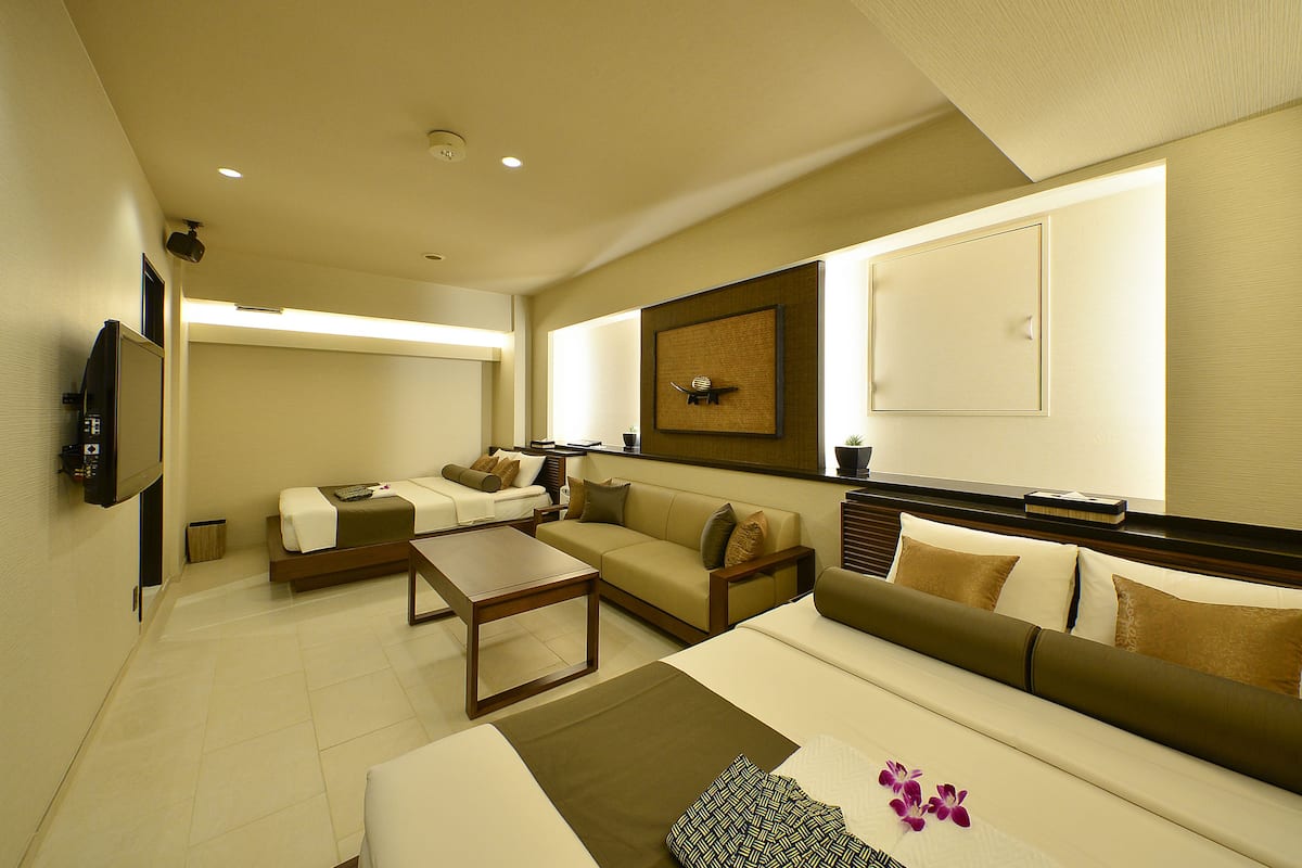 A modern hotel room with a sofa, a bed, a coffee table, and a TV.