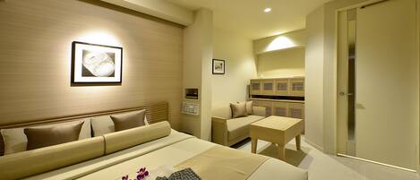 A hotel room with a bed, a sofa, a small table, and a bathroom.
