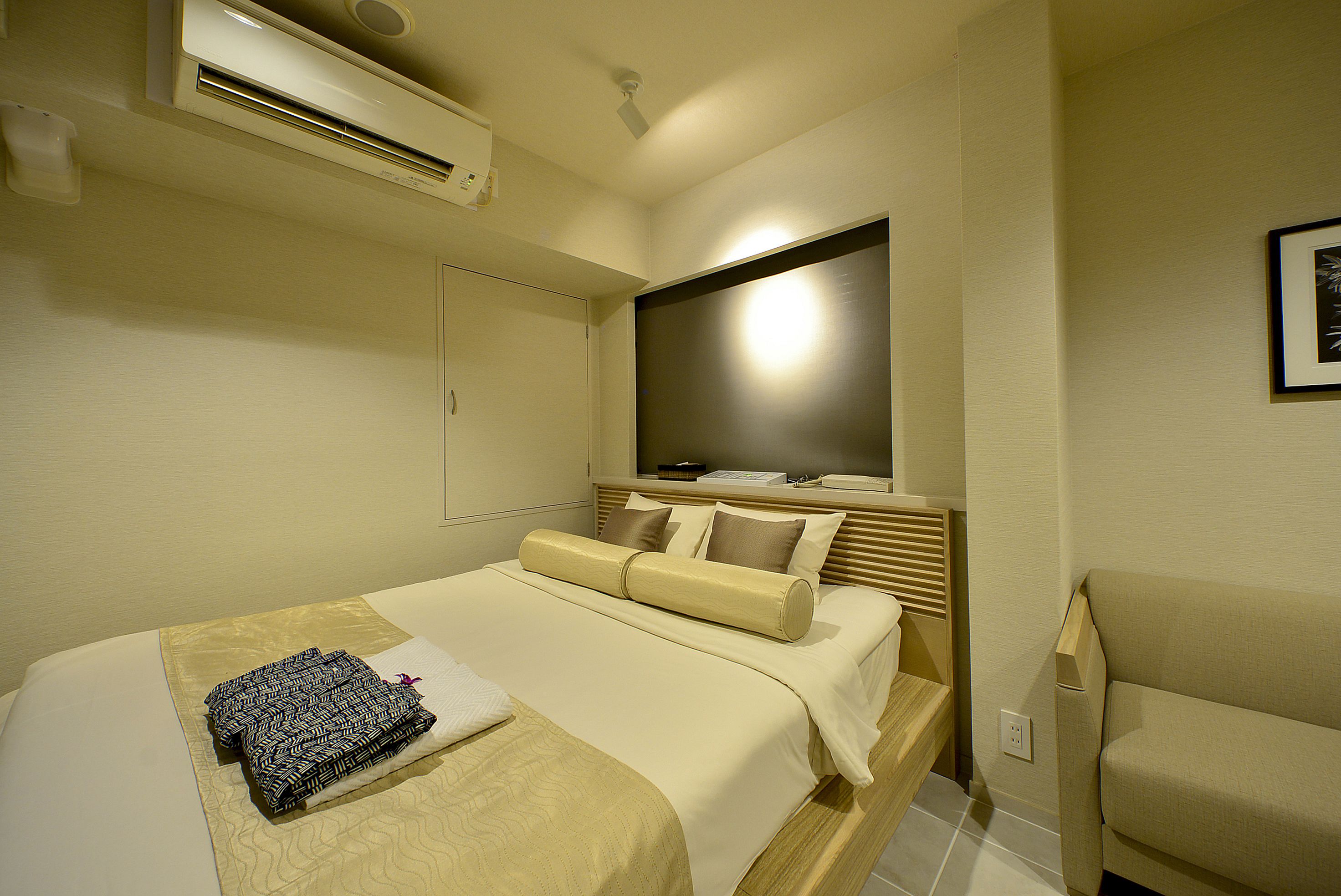 Quarto de hotel com cama, sofá, televisão e janela.