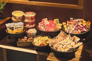 A buffet table with various packaged foods and condiments. - Ikebukuro Retro Hotel (Tokyo)