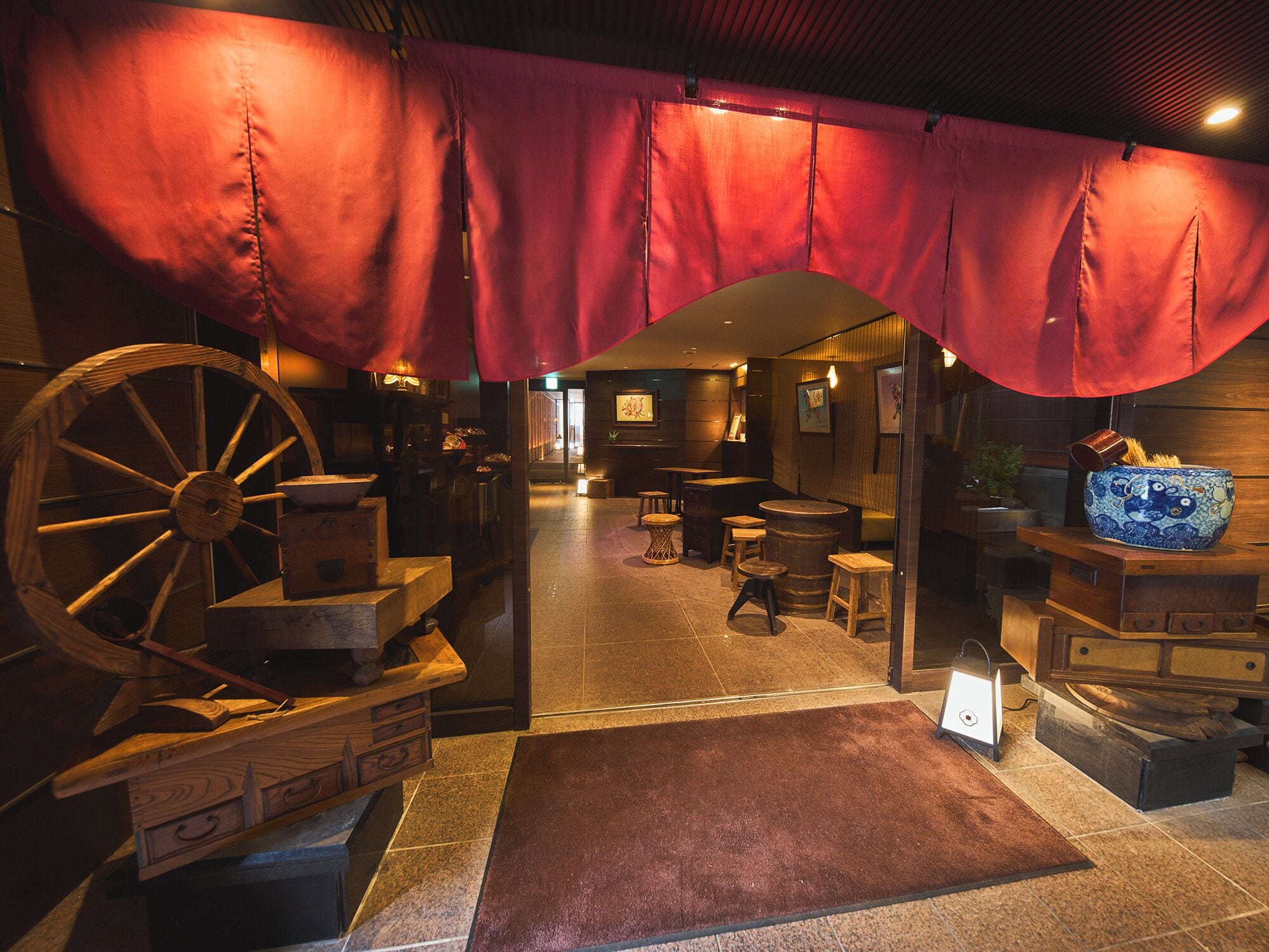 A traditional interior with a wooden wheel, a red curtain, and a rustic wooden table.
