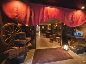A traditional interior with a wooden wheel, a red curtain, and a rustic wooden table. - Ikebukuro Retro Hotel (Tokyo)