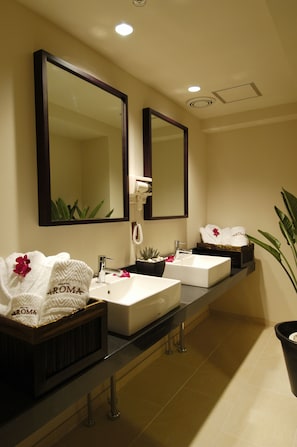 A hotel bathroom with two sinks, a large mirror, and a potted plant.
