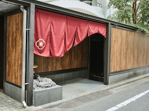 A building with a covered entrance, a wooden facade, and a red awning with a star symbol. - Ikebukuro Retro Hotel (Tokyo)