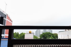A view through a window with a building, a large yellow spherical object on top, and high-rise buildings in the background. - Mango 10 House (Bangkok)