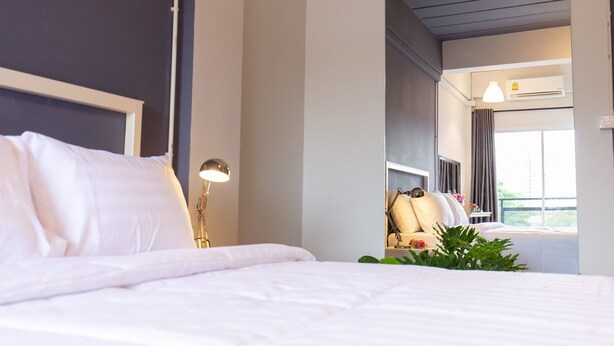 A hotel room with a bed, bedside lamp, and a view of the balcony. - Mango 10 House (Bangkok)