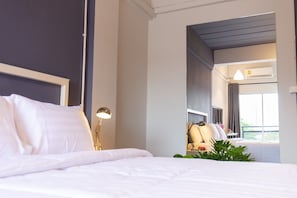 A hotel room with a bed, bedside lamp, and a view of the balcony. - Mango 10 House (Bangkok)