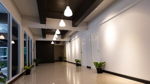 A modern hallway with pendant lighting, potted plants, and a reflective floor. - Mango 10 House (Bangkok)