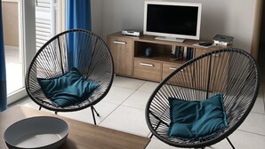 Un soggiorno moderno con due poltrone dal design essenziale e struttura in metallo nero, un tavolino in legno, un televisore su un mobile in legno e un quadro raffigurante due persone appeso alla parete.