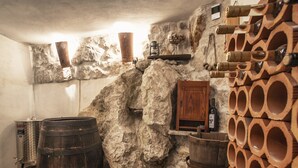 Una cantina rustica con pareti in pietra, botti di legno e un armadio in legno.