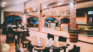 A spacious cafe with brick walls, wooden tables, and a bar area. - Malagos Garden Resort (Davao)
