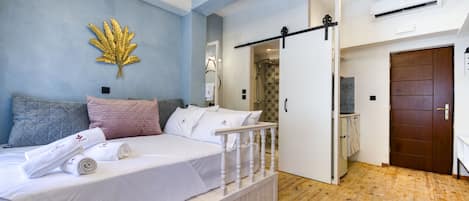 Ein Schlafzimmer mit Bett, Kissen, einer Wanddekoration, Holzboden und einer Tür.