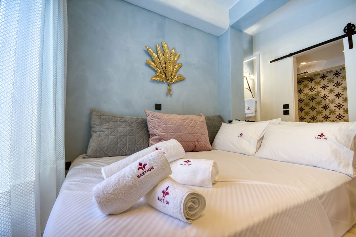 Een net opgemaakt bed met witte lakens en een opgerolde handdoek met een logo.