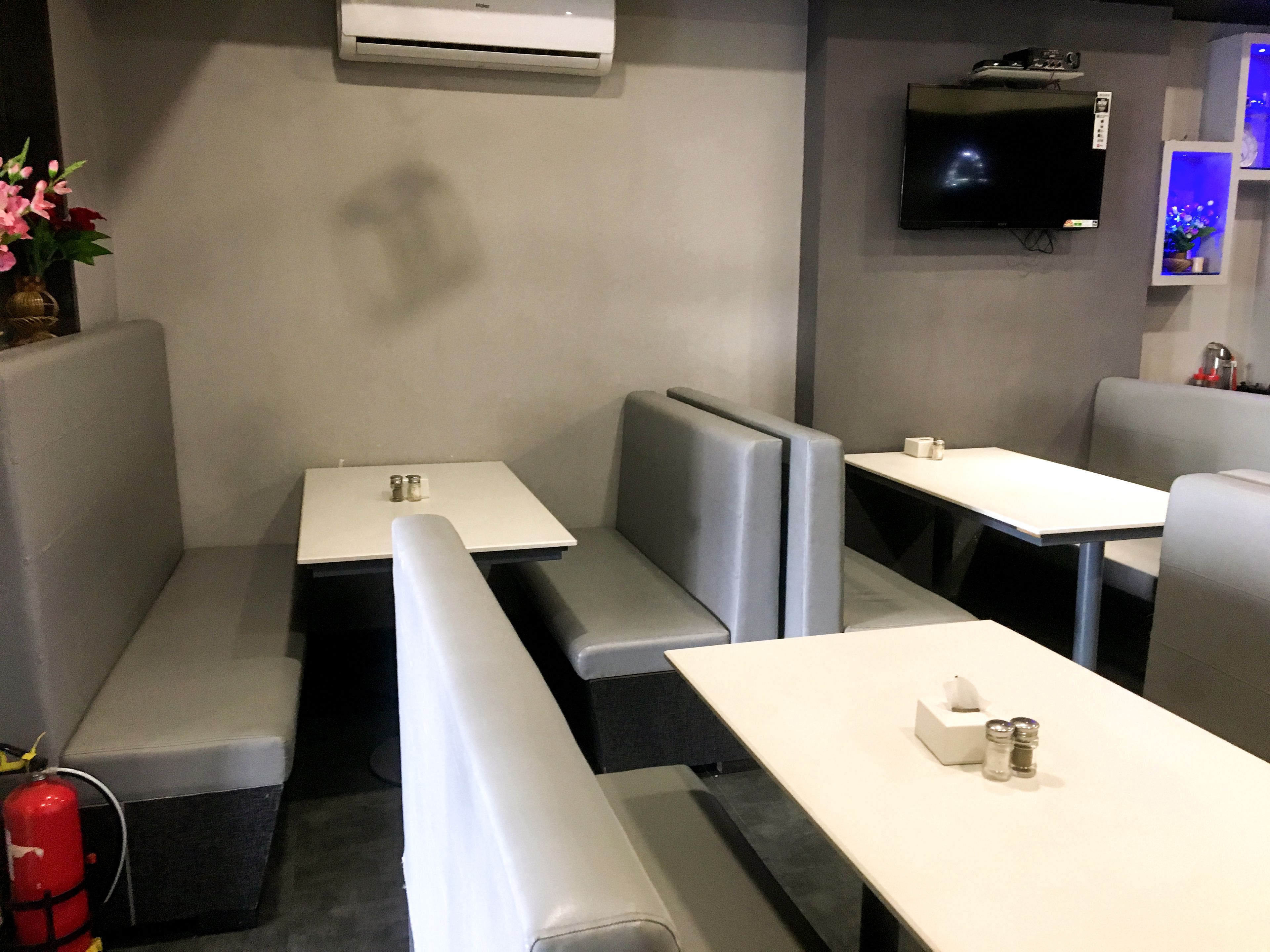 Ein modernes Restaurantambiente mit Sitzecken, Tischen und einem Flachbildfernseher an der Wand.