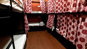 Un dormitorio con literas, cortinas estampadas y suelo de madera.