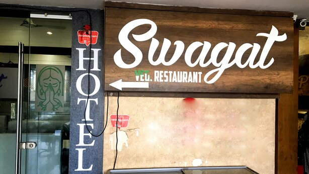 Señal de restaurante vegetariano Swagat con una flecha que apunta a la izquierda, indicando el camino al restaurante.