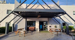 A modern building with a triangular roof structure, outdoor seating area with tables and chairs, and a visible entrance. - Hotel Thania (Frontignan)