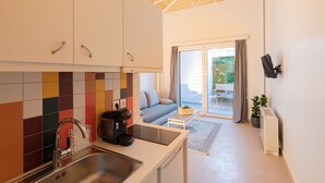 Una cocina moderna con un salpicadero de colores, estufa empotrada y un lavamanos. Hay una puerta corrediza de vidrio que da a un balcón con un sofá y una mesita.