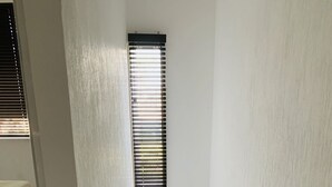 A narrow stairway with two windows, each with horizontal blinds, leading to a lower level.