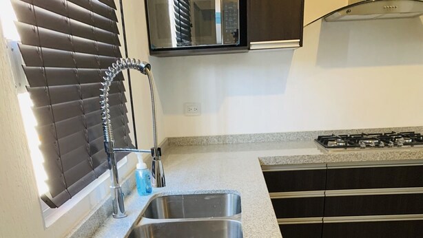 A kitchen with granite countertops, stainless steel sinks, and a gas stove.