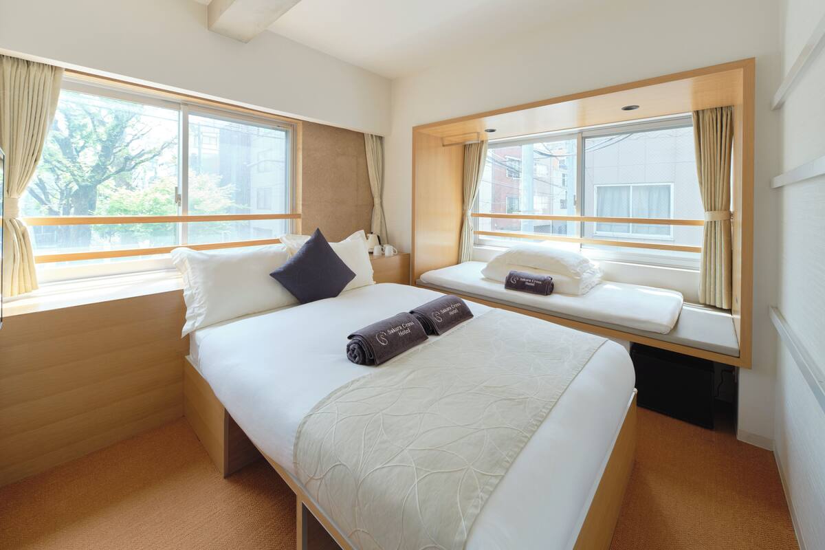 Een hotelkamer met een groot bed, een vensterbank en uitzicht op de stad.