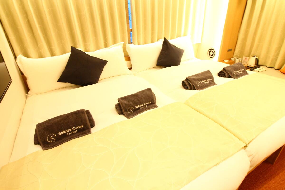 Een hotelbed met een beddekleed met patroon, kussens en twee handdoeken met het logo van het hotel.