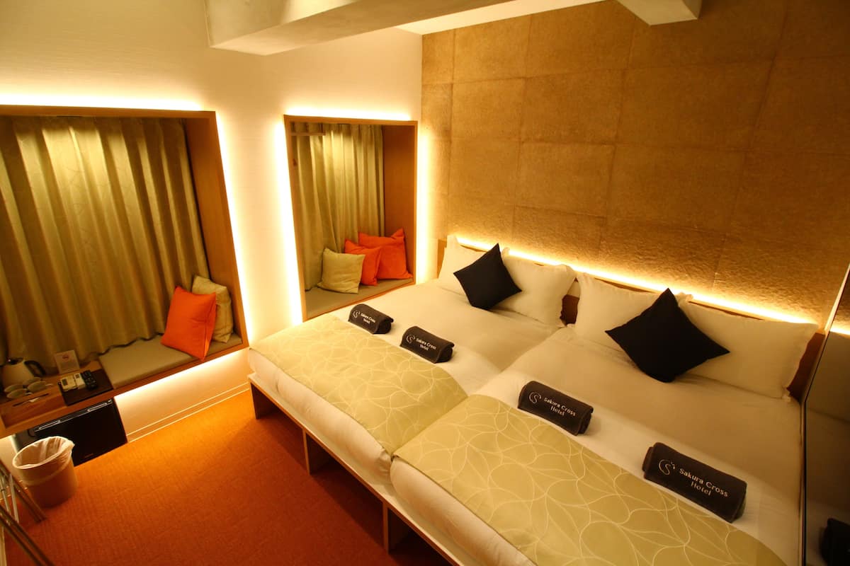 Een hotelkamer met een groot bed, nachtkastje, spiegel en uitzicht op de stad.